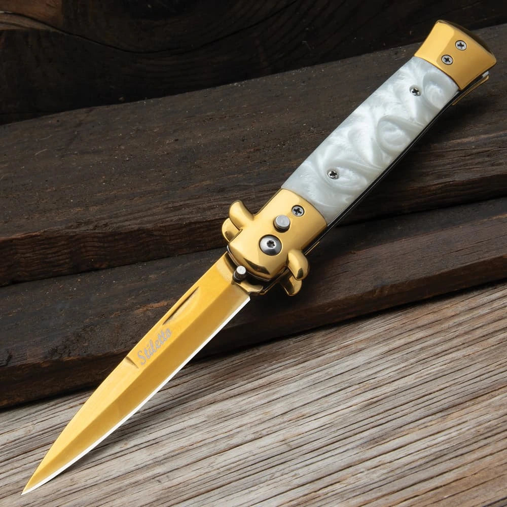 Gold stiletto automatic knife closed with white marble inserts and gold bolsters