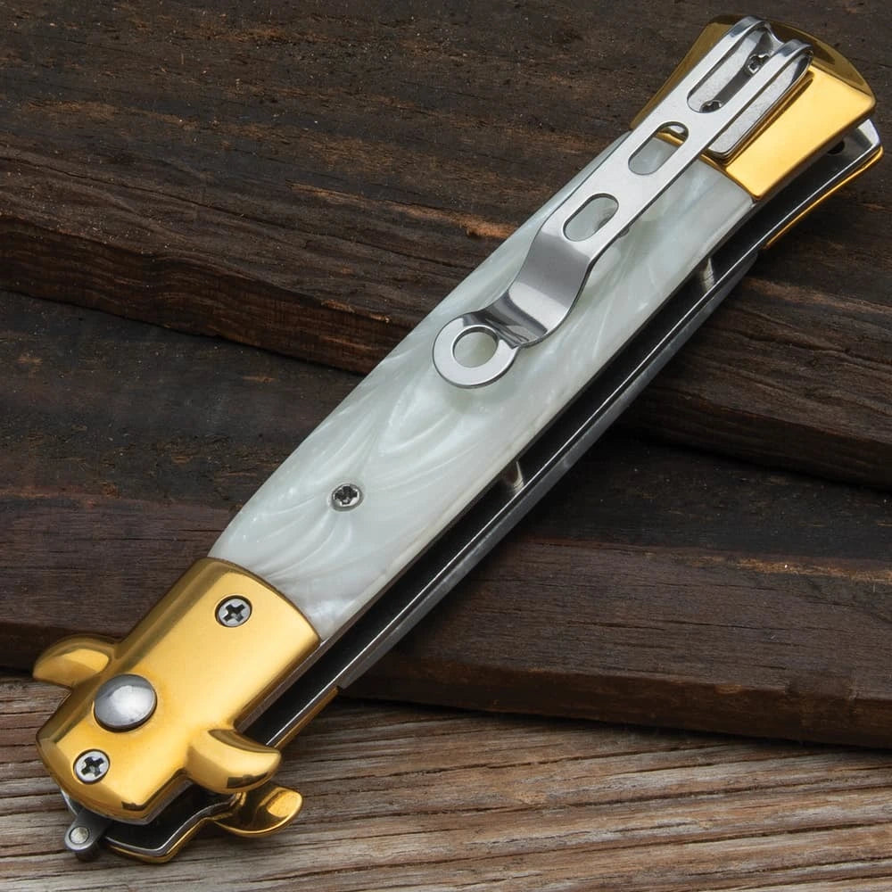 Gold stiletto automatic knife closed with white marble inserts and gold bolsters