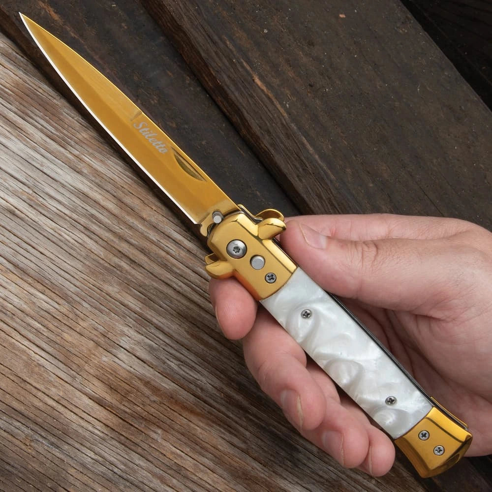 Gold stiletto automatic knife closed with white marble inserts and gold bolsters