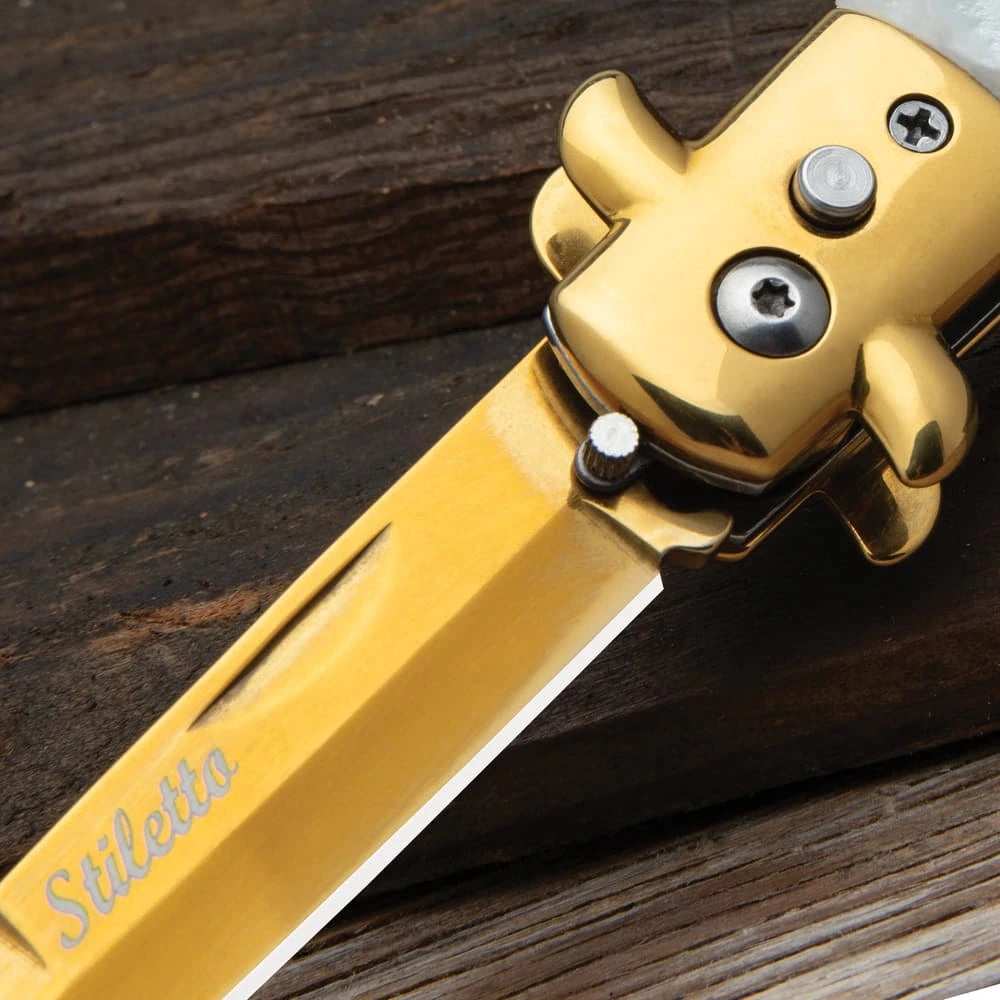 Gold stiletto automatic knife closed with white marble inserts and gold bolsters